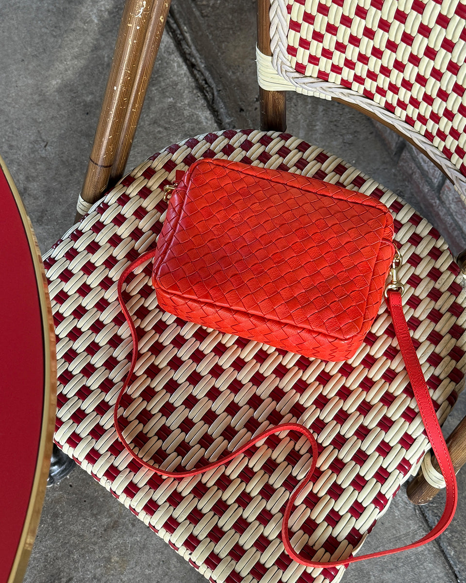 Bright Poppy Diagonal Woven Midi Sac laying on a chair. 