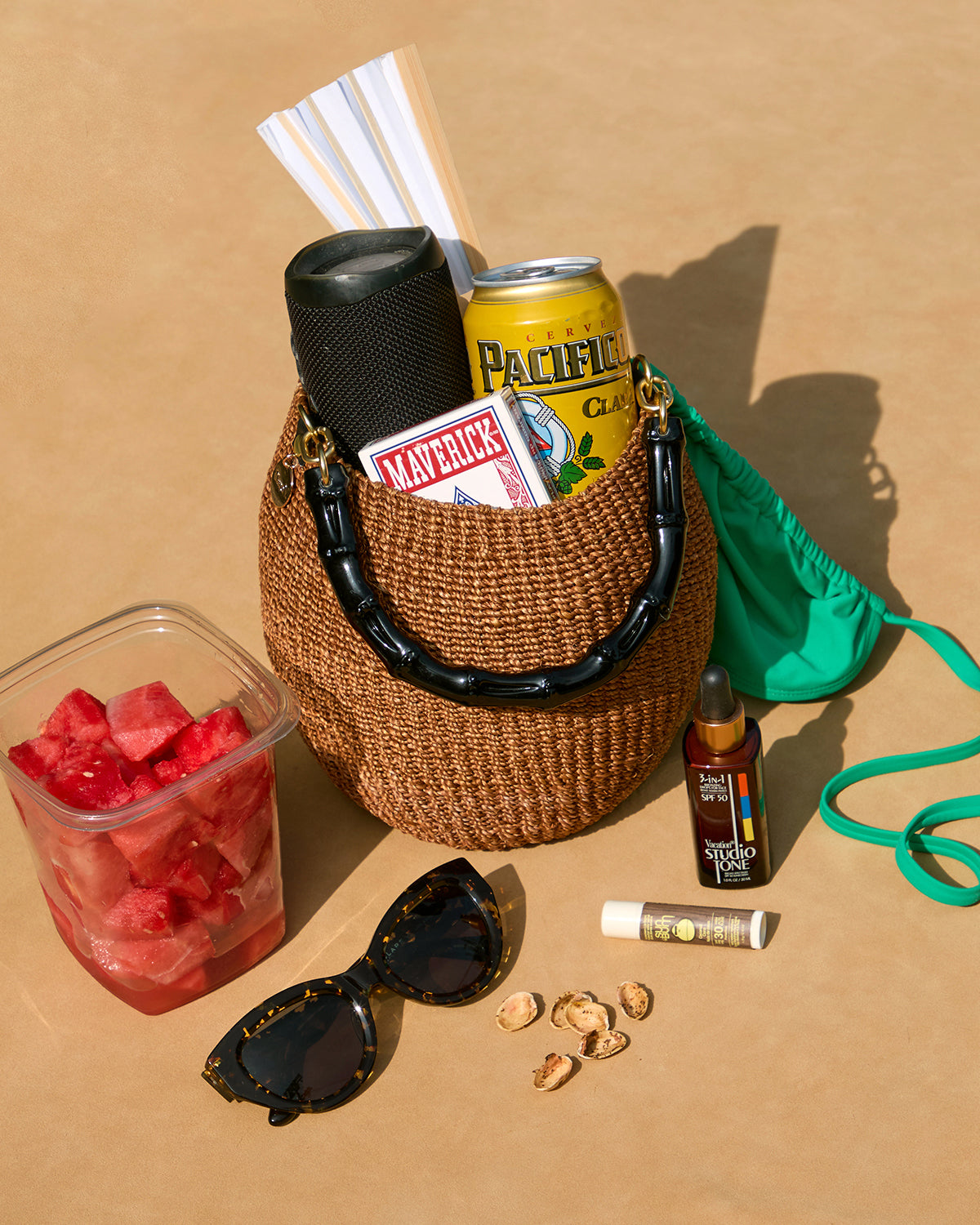 A full Pot de Miel sitting on the floor of a beach with items surrounding it. 