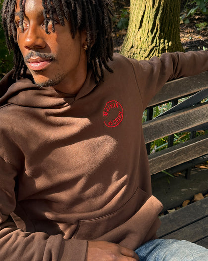Man sitting on a bench wearing the Clare V. x The Dogist Beau Hoodie.