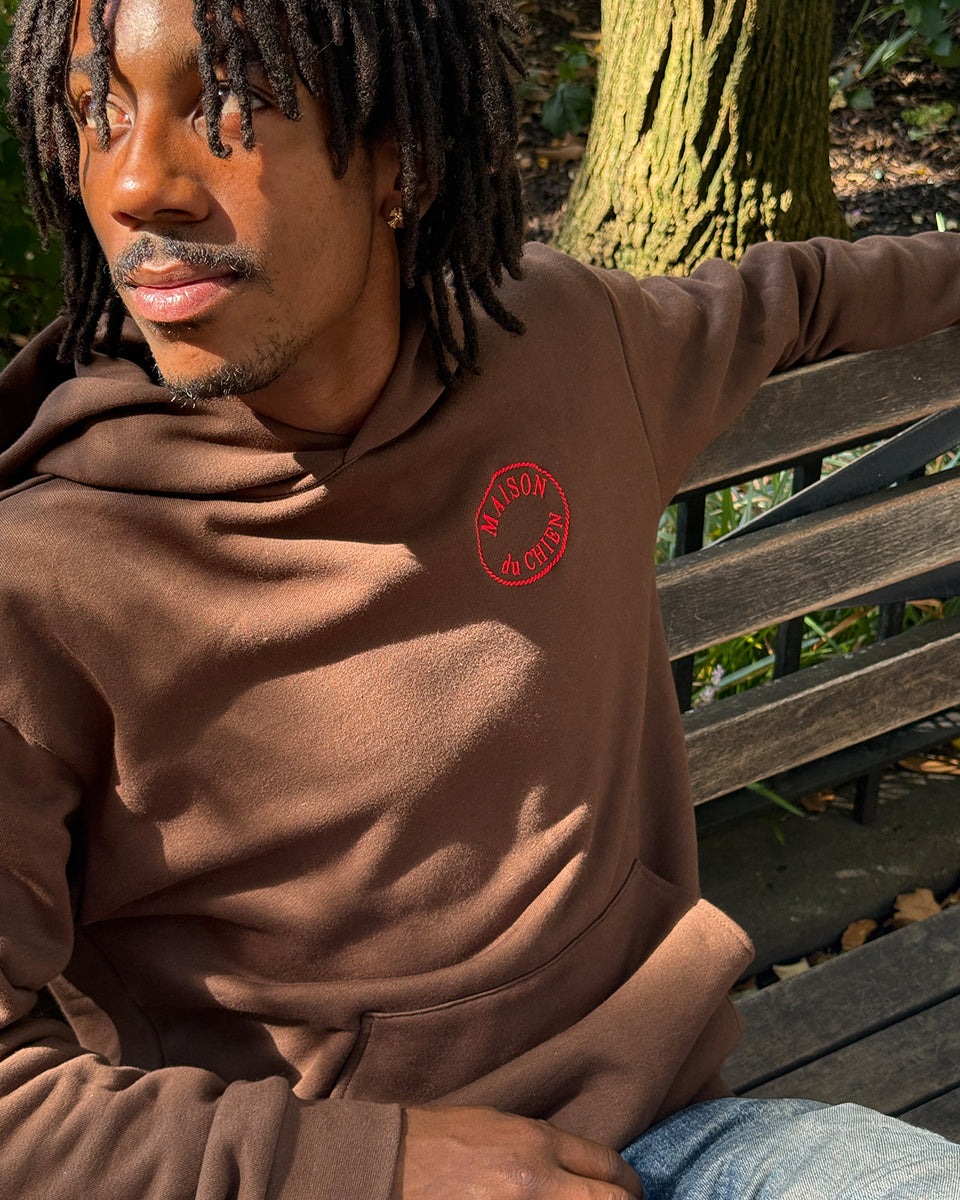 Man sitting on a bench wearing the Clare V. x The Dogist Beau Hoodie.