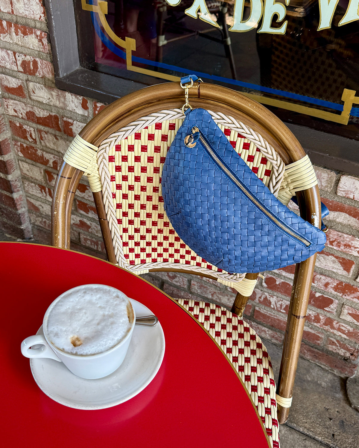 French Blue Diagonal Woven Grande Fanny hanging on a cute chair in a cafe. 
