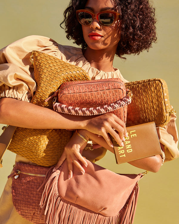 Model carrying as assortment of Clare V. handbags. 