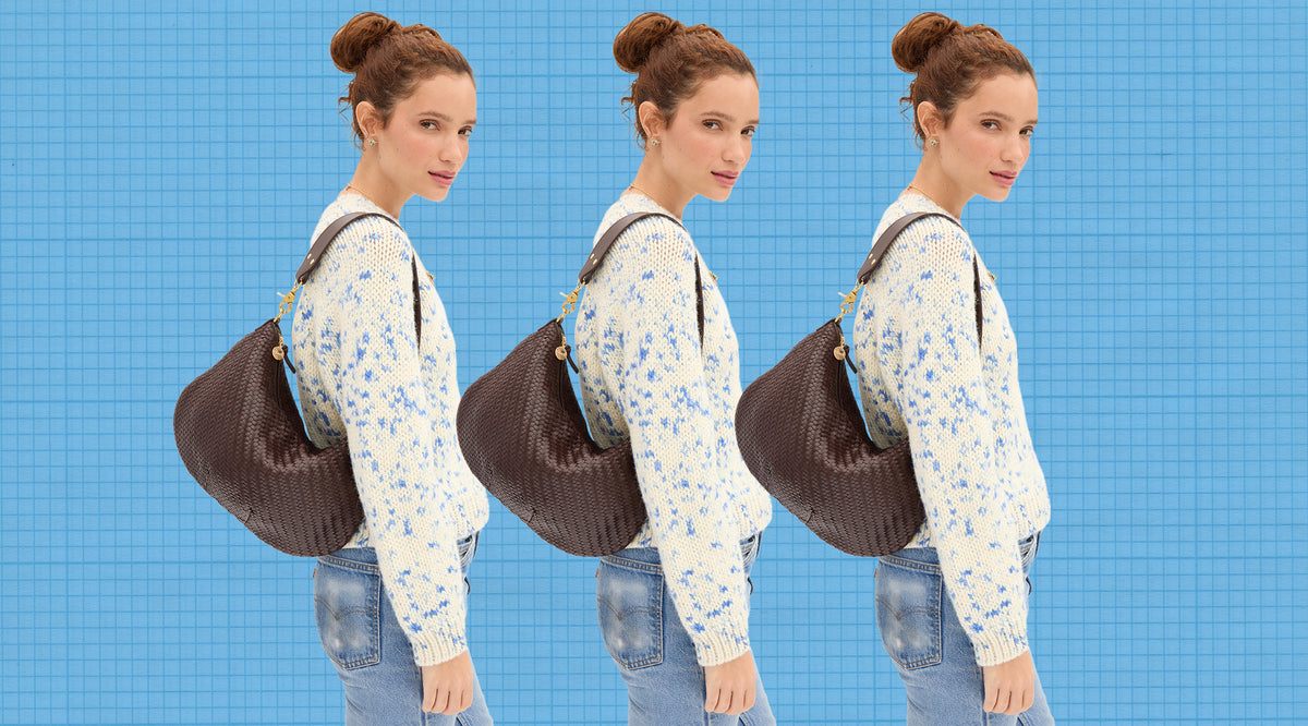 Model wearing the Cream/Cobalt Speckle Le Court Sweater and carrying the Chocolate Woven Moyen Messenger. 