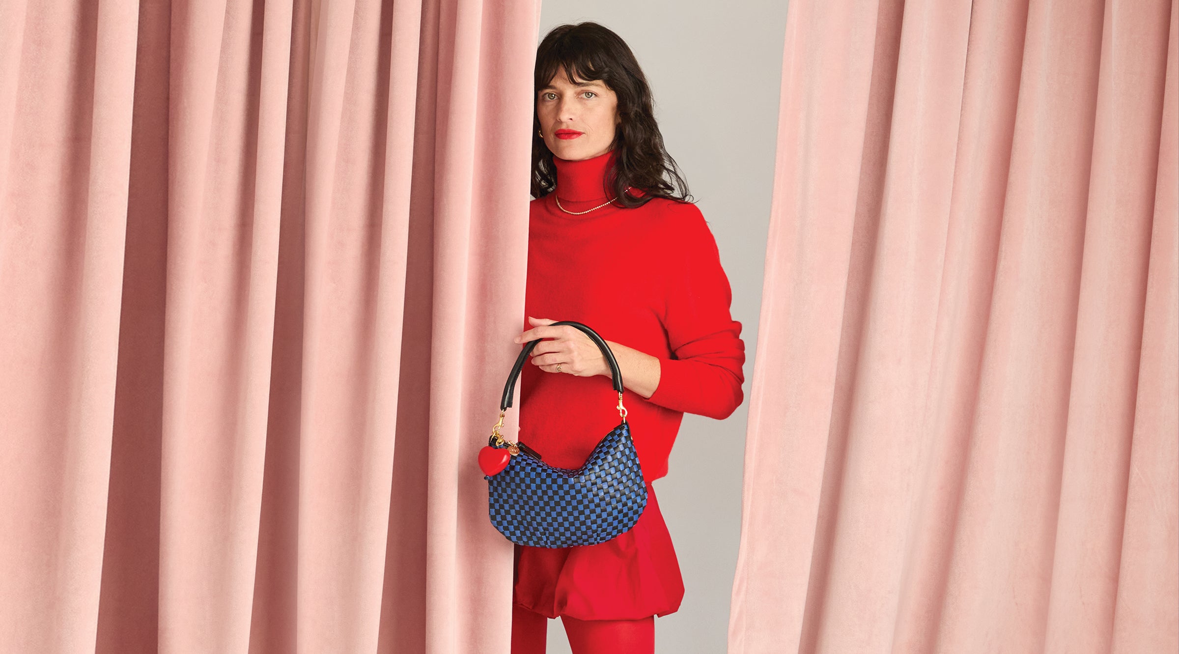 Model carrying the Black/Cobalt Petit Moyen with Red Heart Fob attached to it.