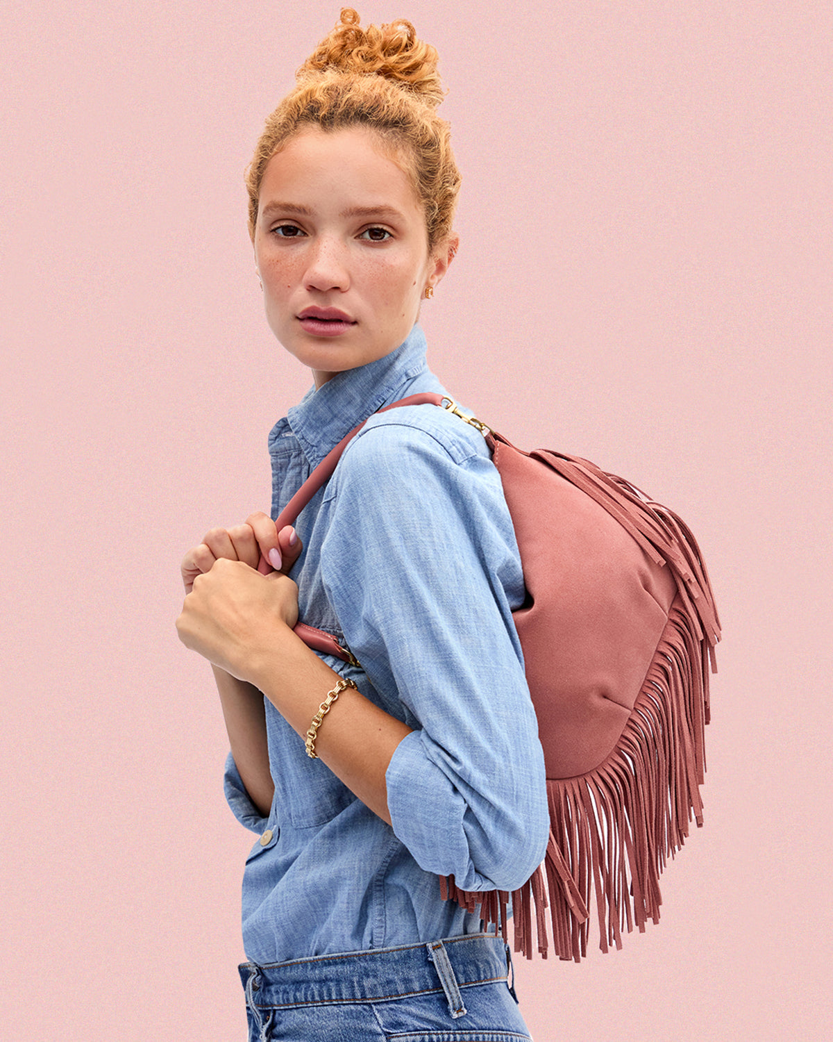 Model carrying the Rose Clay Suede Petit Moyen Messenger with Fringe.