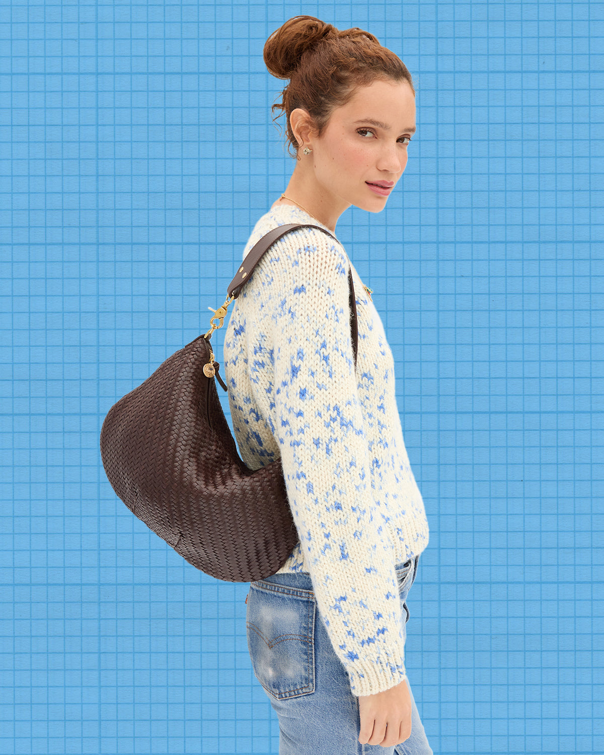 Model wearing the Cream/Cobalt Speckle Le Court Sweater and carrying the Chocolate Woven Moyen Messenger. 