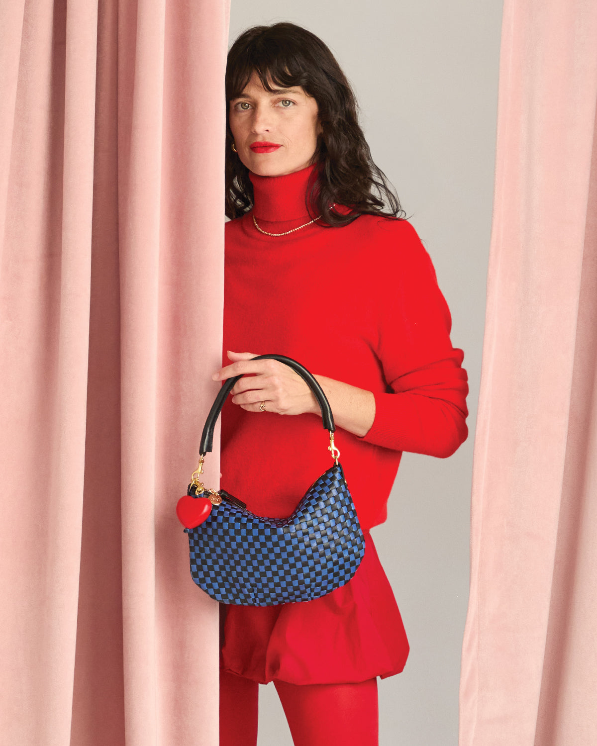 Model carrying the Black/Cobalt Petit Moyen with Red Heart Fob attached to it.