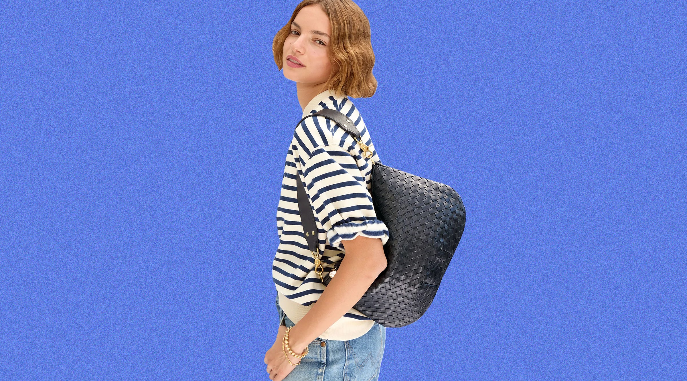 Model wearing the Cream/Navy Stripe Short Sleeve Oversized Sweatshirt with jeans and carrying the Twilight Navy Diagonal Woven Moyen Messenger over her shoulder. 