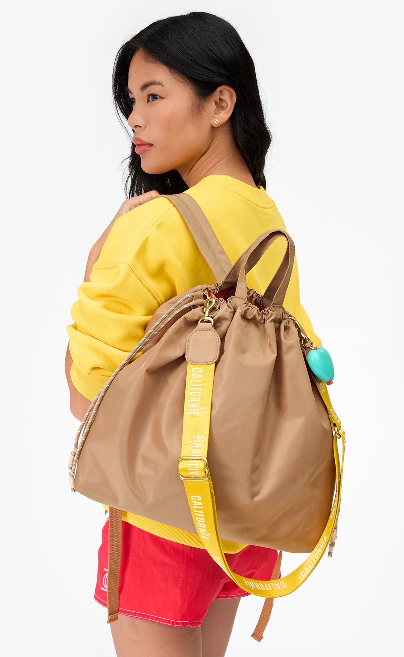 Model wearing the Latte Sac Tout Backpack with Turquoise Grande Heart Fob. 