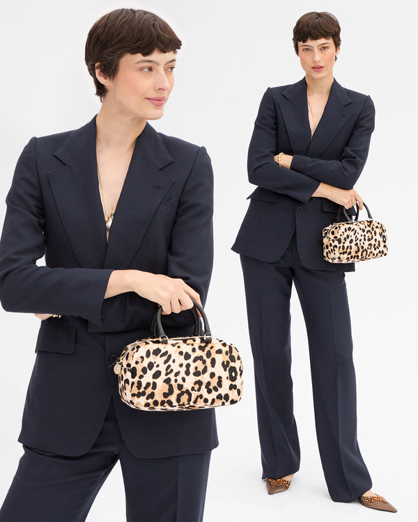 Model carrying the Snow Leopard Petite Claudine as a top handle bag. 