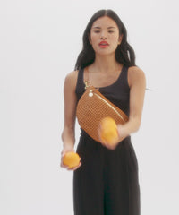 Model juggling oranges while carrying the Tan Rattan Grande Fanny over her chest. 