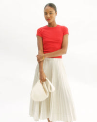 Model walking by and showing different ways to carry the Cream Woven Moyen Messenger using the Shoulder Strap.