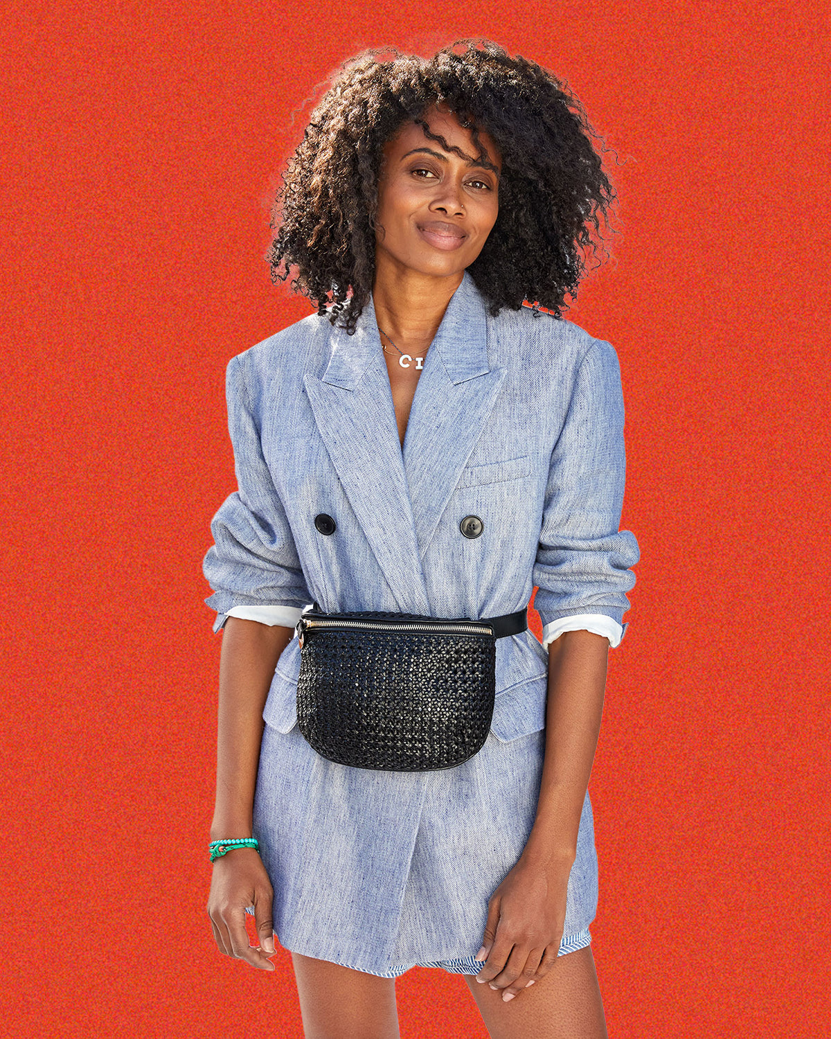 Mecca wearing the Black Rattan Fanny Pack around her waist over a chambray blazer.