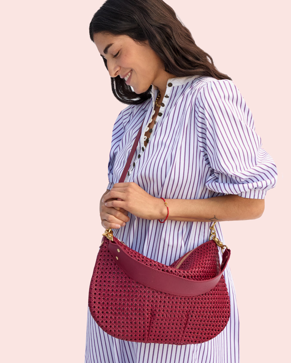 Model carrying the Plummy Rattan Moyen Messenger as a crossbody bag. 