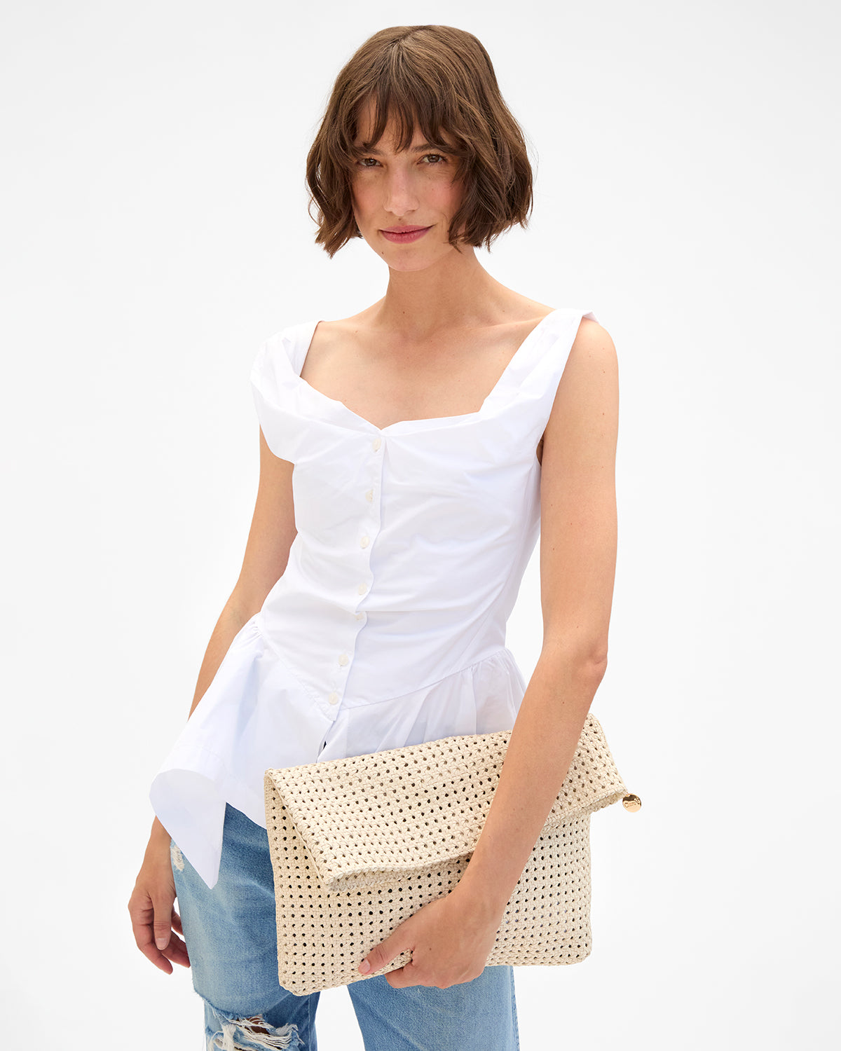Model carrying the Cream Rattan Carryall Clutch with Tabs. 