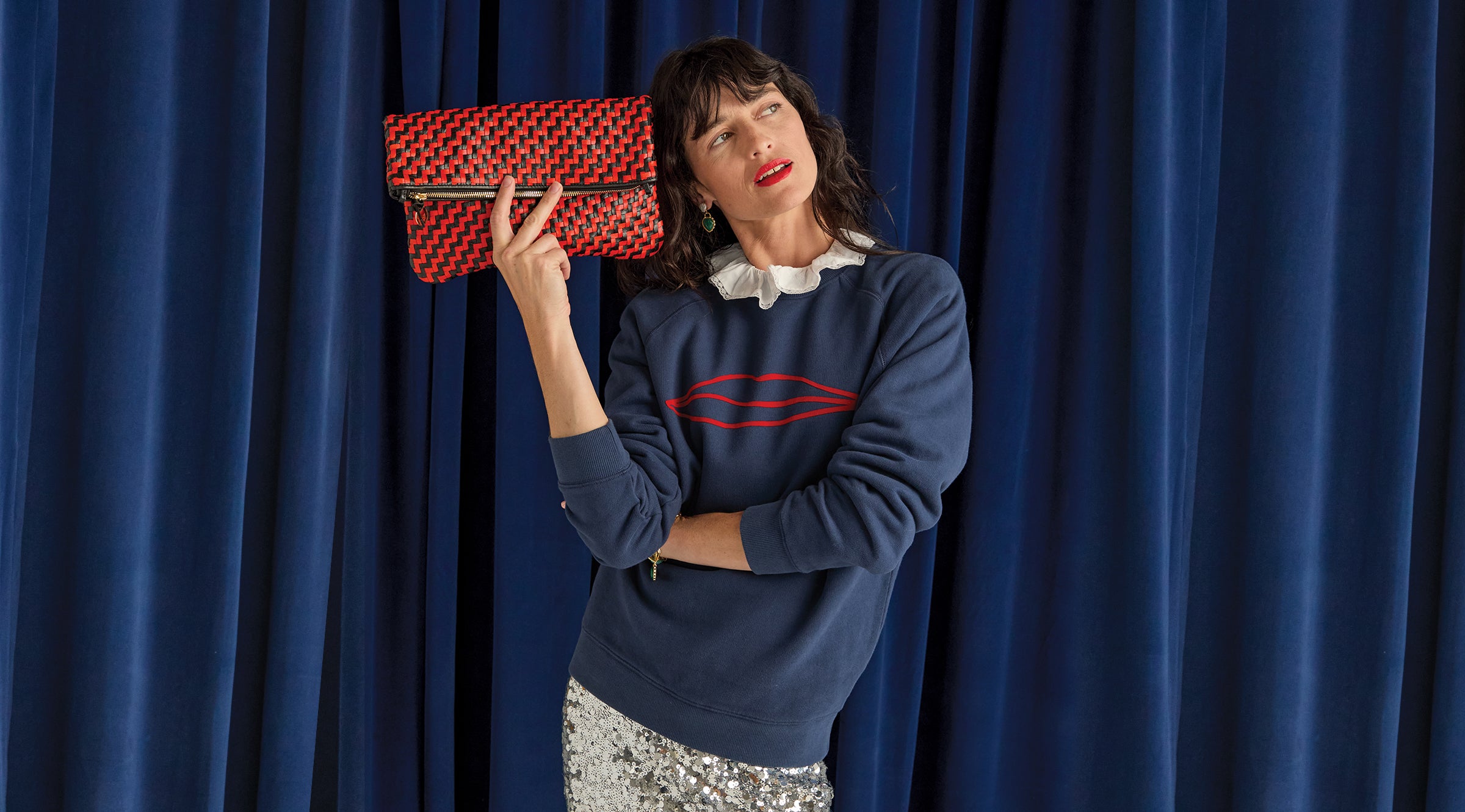 Model holding the Black/Poppy Woven Foldover Clutch with Tabs.