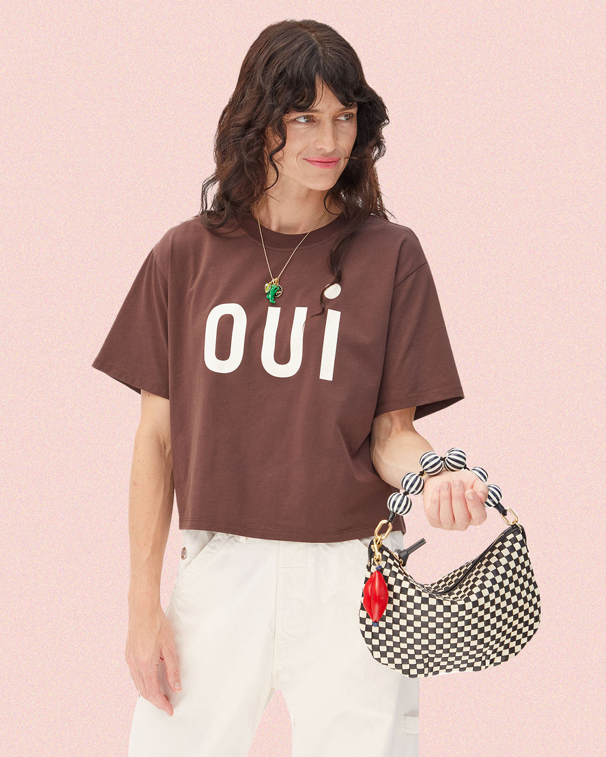 Model wearing the Oui Le Carré Tee and carrying the Petit Moyen in Black/Cream Woven with an additional Top Handle Strap and Lips Fob.