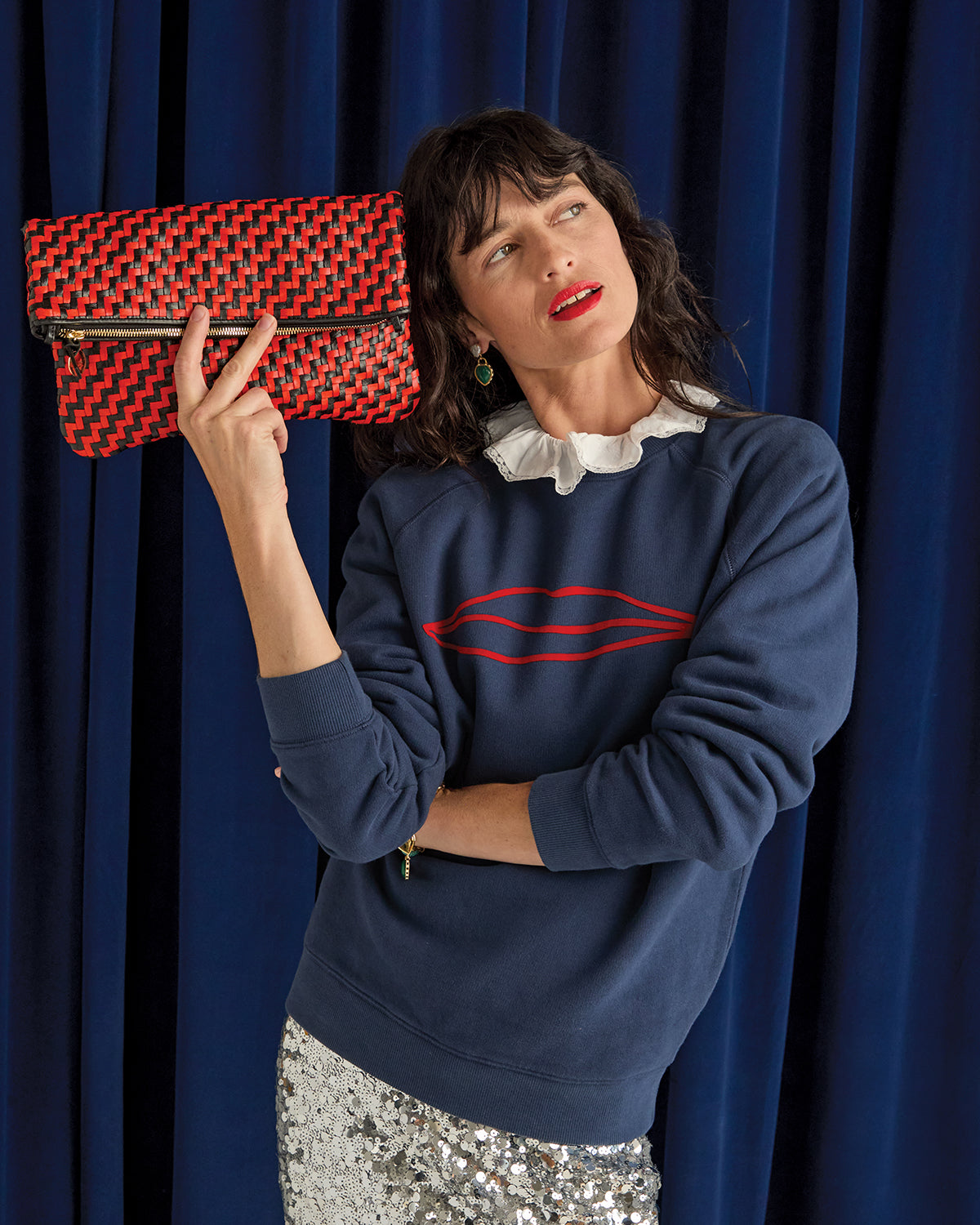 Model holding the Black/Poppy Woven Foldover Clutch with Tabs.