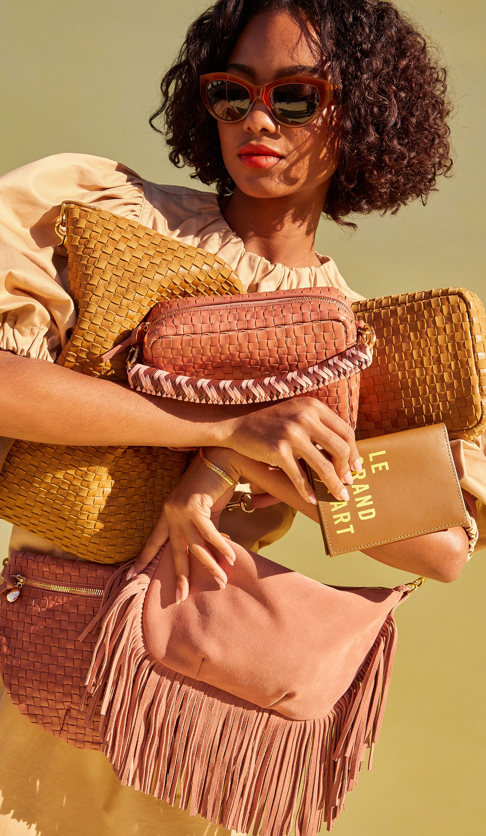 Model carrying as assortment of Clare V. handbags. 