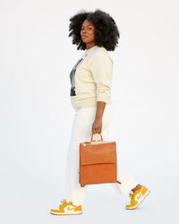 candice talking a step while carrying the cuoio perf Agnes Backpack by its top handle