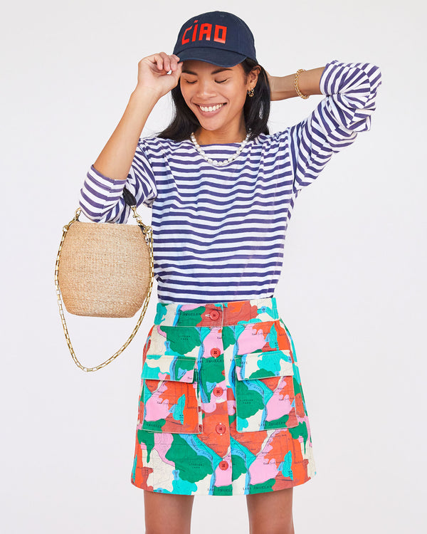 sandra wearing a striped shirt and the multi map print ginette mini with the Navy ciao Baseball Hat and the cream pot de miel with brass box chain shoulder strap