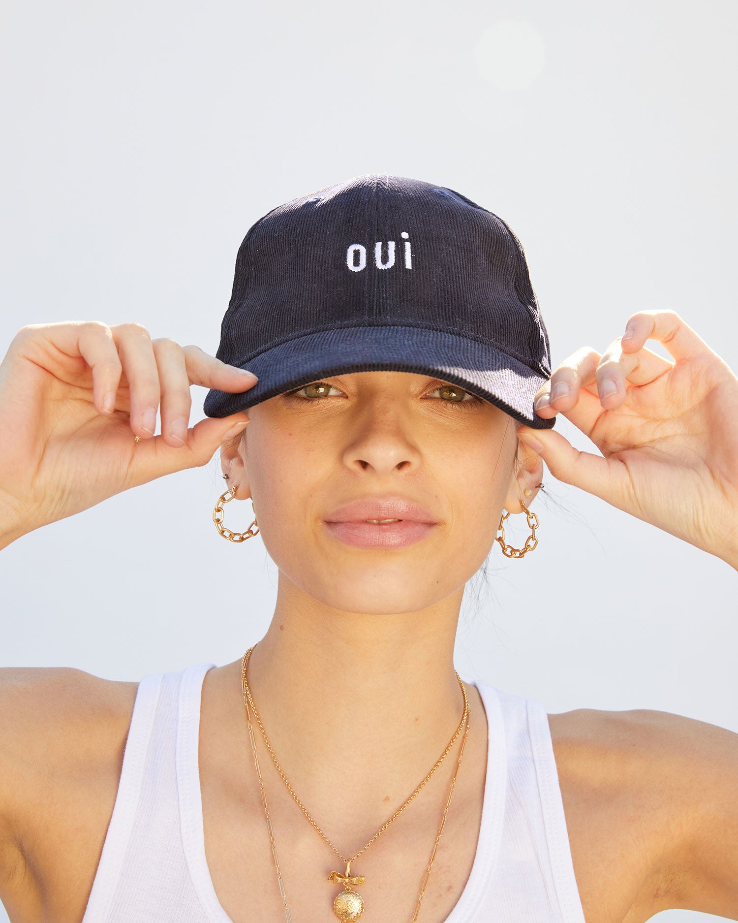 Aurelia wearing the Navy Corduroy Baseball Hat and touching the brim with her hands
