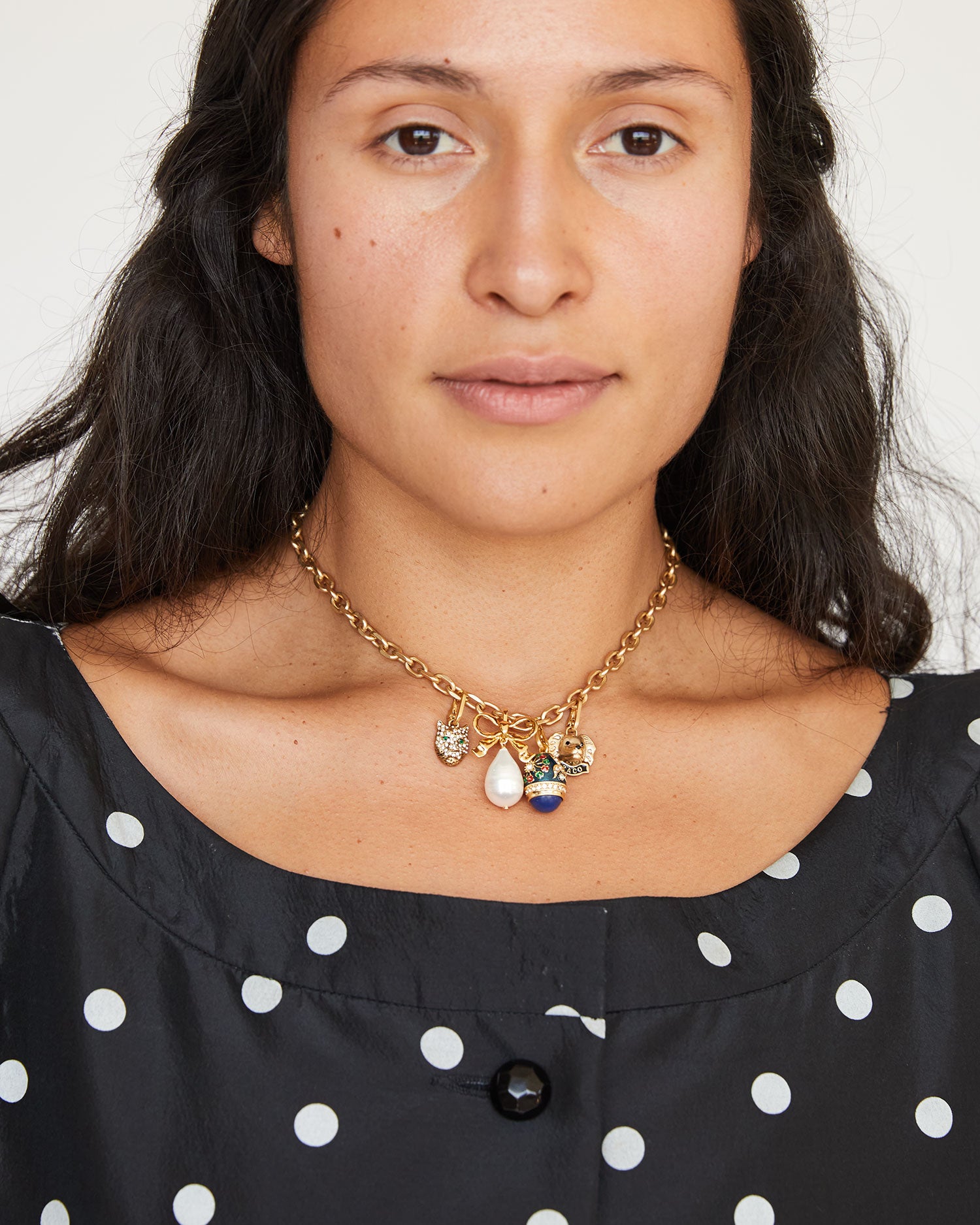 Andrea wearing the Bow & Pearl Charm on the CV chain charm necklace with other charms
