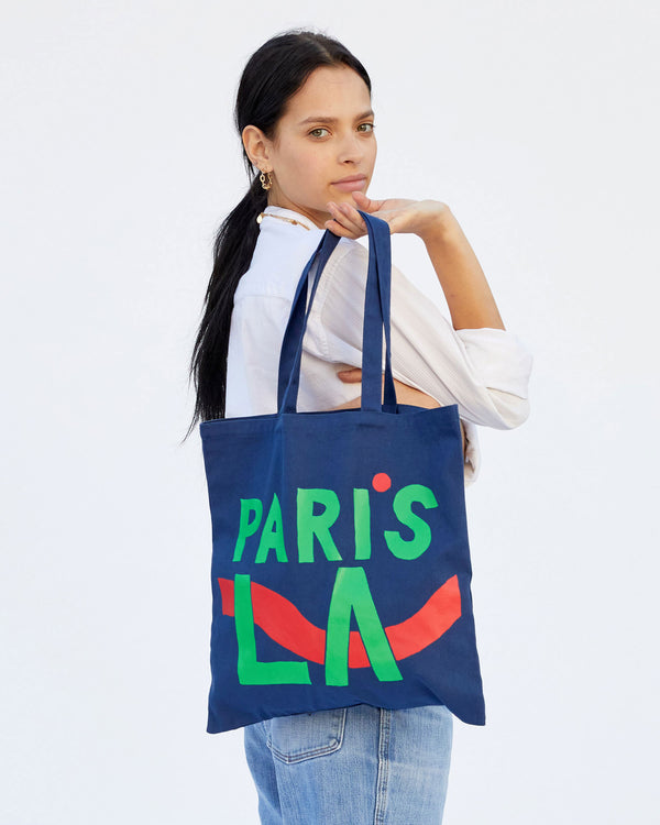 Aurelia holding the  Navy Paris L.A. Canvas Store Tote over her shoulder with her right arm