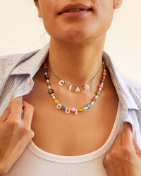 andrea in a white tank top and a blue and white striped overshirt wearing the Ciao Pearl Necklace with the Oui Multi Flower Strand Necklace