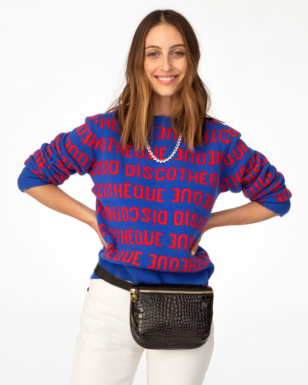 Frannie wearing the Cobalt & Poppy Discotheque Classic Sweater with white pants and the black croco fanny pack around her waist