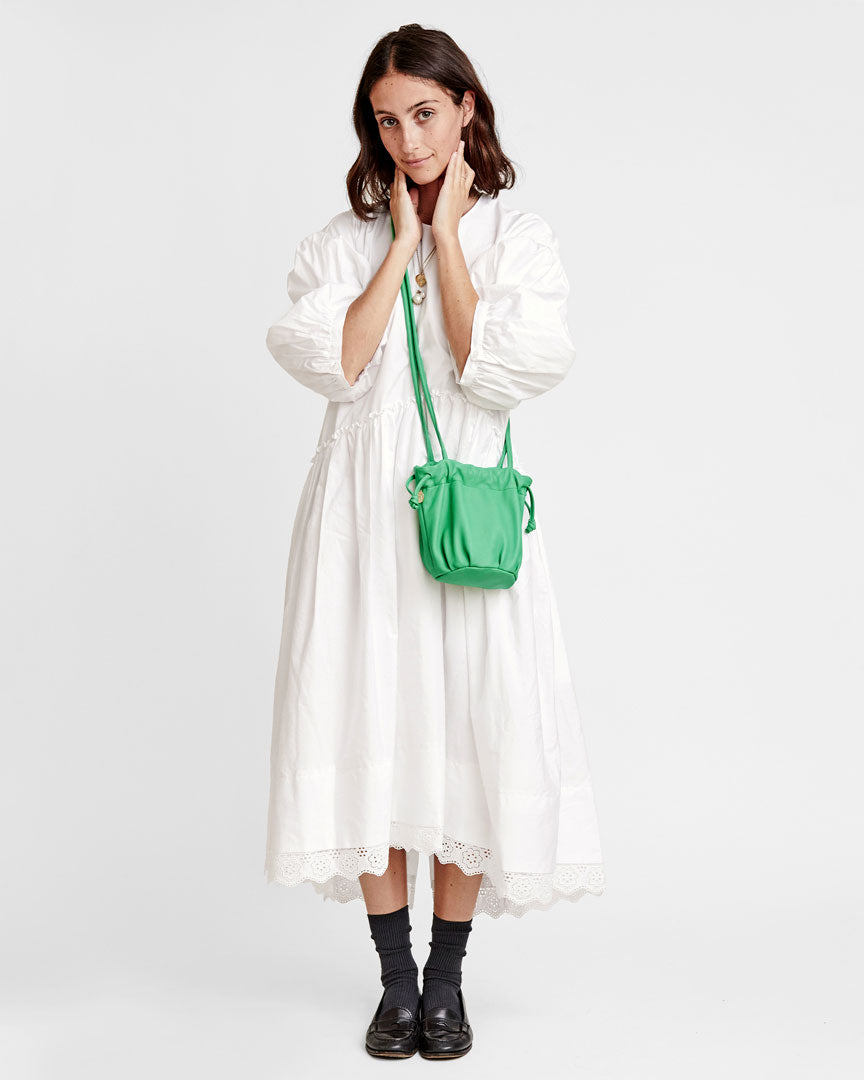 frannie wearing a white dress with black loafers. she has on the Parrot Green Emma crossbody