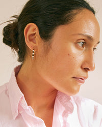 Andrea wearing a light pink button up shirt with the Black & Cream Enamel Stripe Hoop Earrings