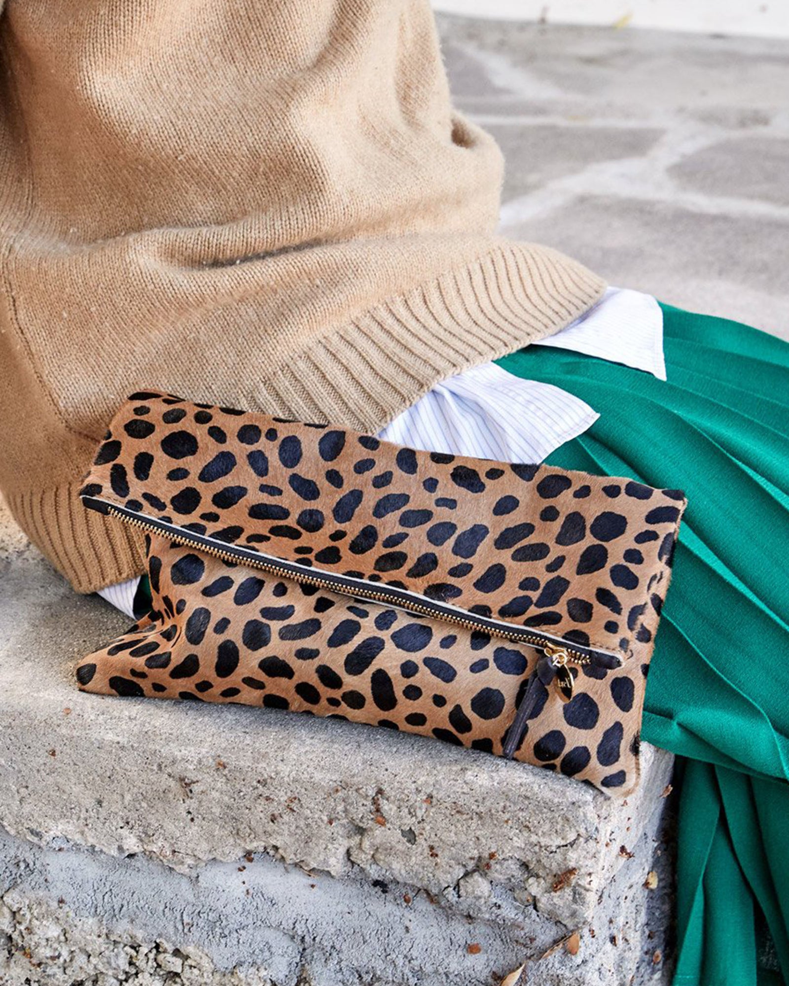 Foldover Clutch in Leopard Hair sitting next to Mecca on a step