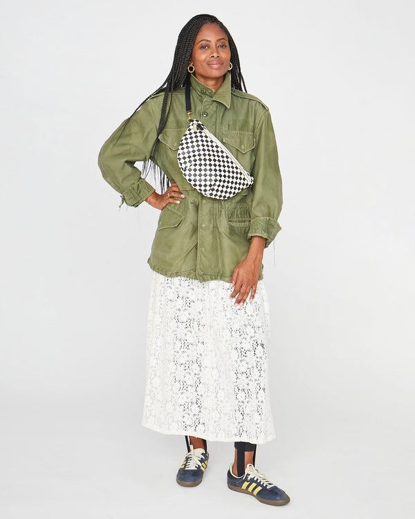 mecca with one hand on her hip, wearing the Black & Cream Checker Grande Fanny across her chest over her army green jacket