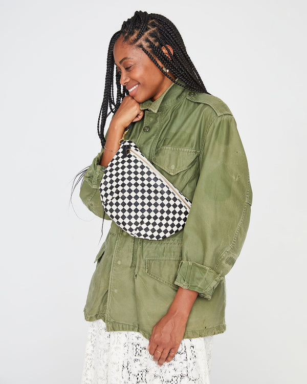 mecca wearing an army green jacket and a white lace skirt with the Black & Cream Checker Grande Fanny worn across her chest