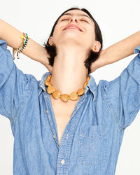 Athena wearing the Natural Heart Collar with a denim shirt and jeans with her hands behind her head