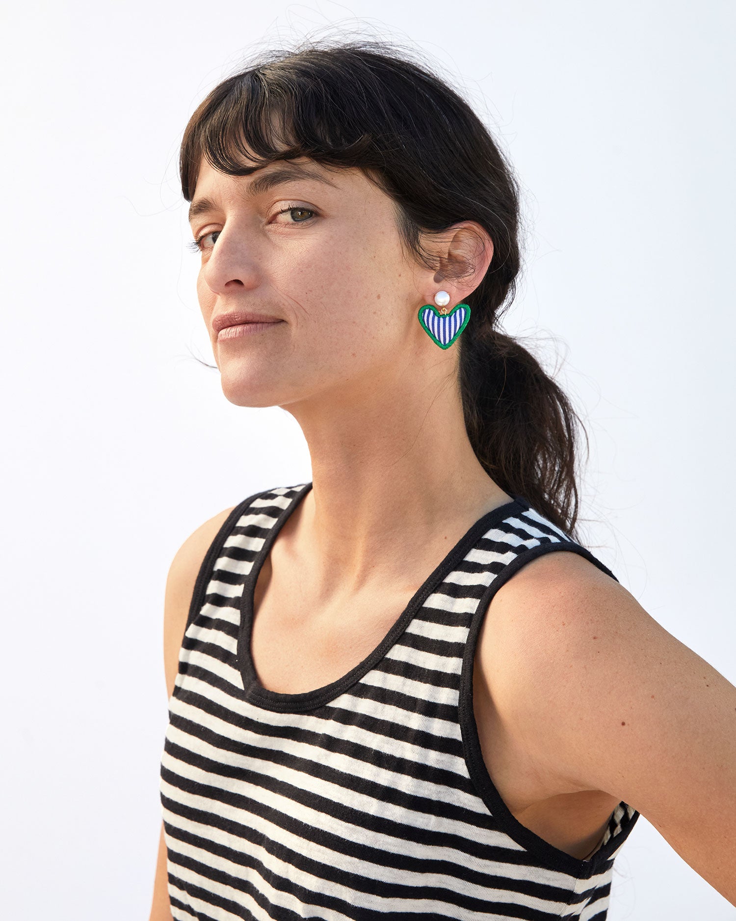 danica looking at the camera in a striped tank top wearing the Heart Pillow Statement Earrings