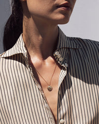 Model wearing the Kathryn Bentley Athena Greek Coin Necklace with a striped button up shirt 