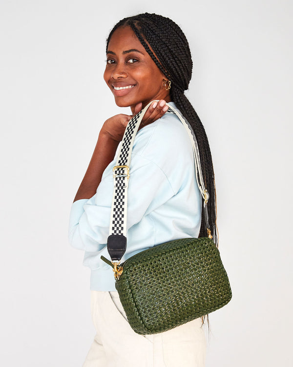 mecca holding the army rattan marisol  by her shoulder by the black and cream adjustable webbing strap