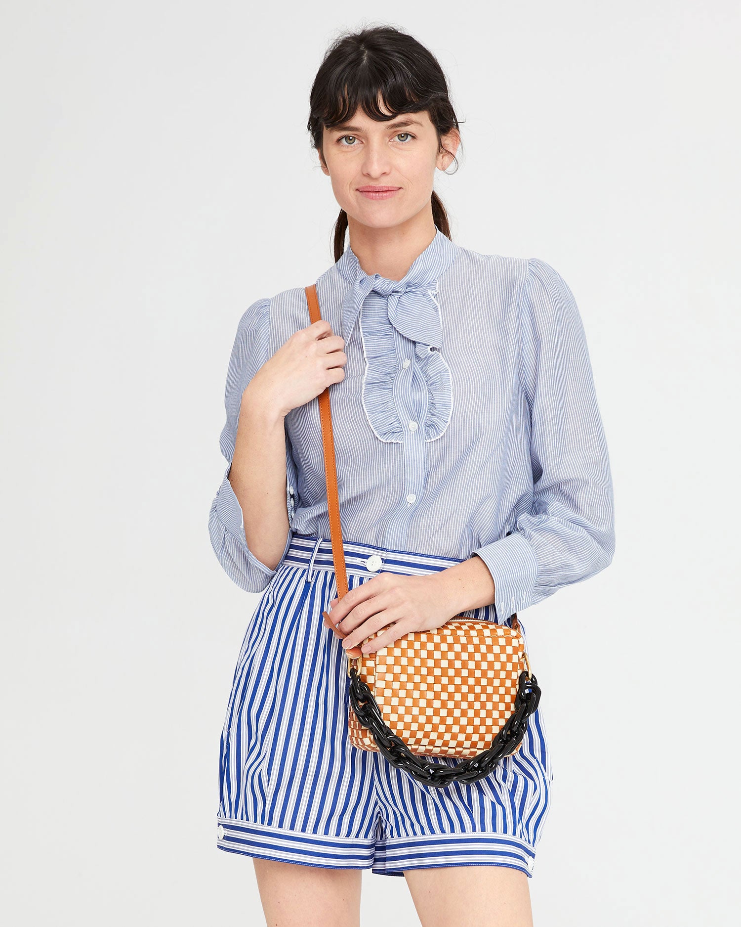 Danica wearing the Natural & Cream Woven Checker Midi Sac crossbody with the black resin shortie strap hanging off of it 