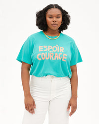 Candace wearing the Desert Turquoise Espoir et Courage Original Tee tucked in to white jeans