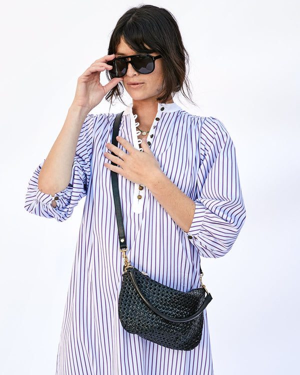 Dancia Wearing a Striped Dress with the Black Rattan Petit Moyen Worn Crossbody