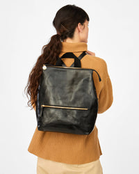 danica wearing the Black Rustic Remi Backpack on her back over a tan sweater 