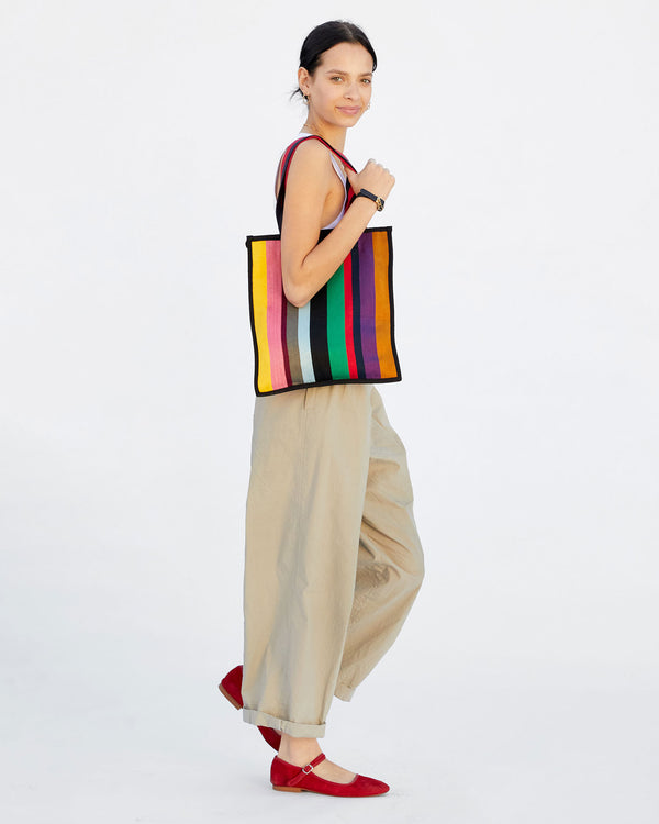 Aurelia wearing a white tank top and khakis with the Ribbon Tote with red flats