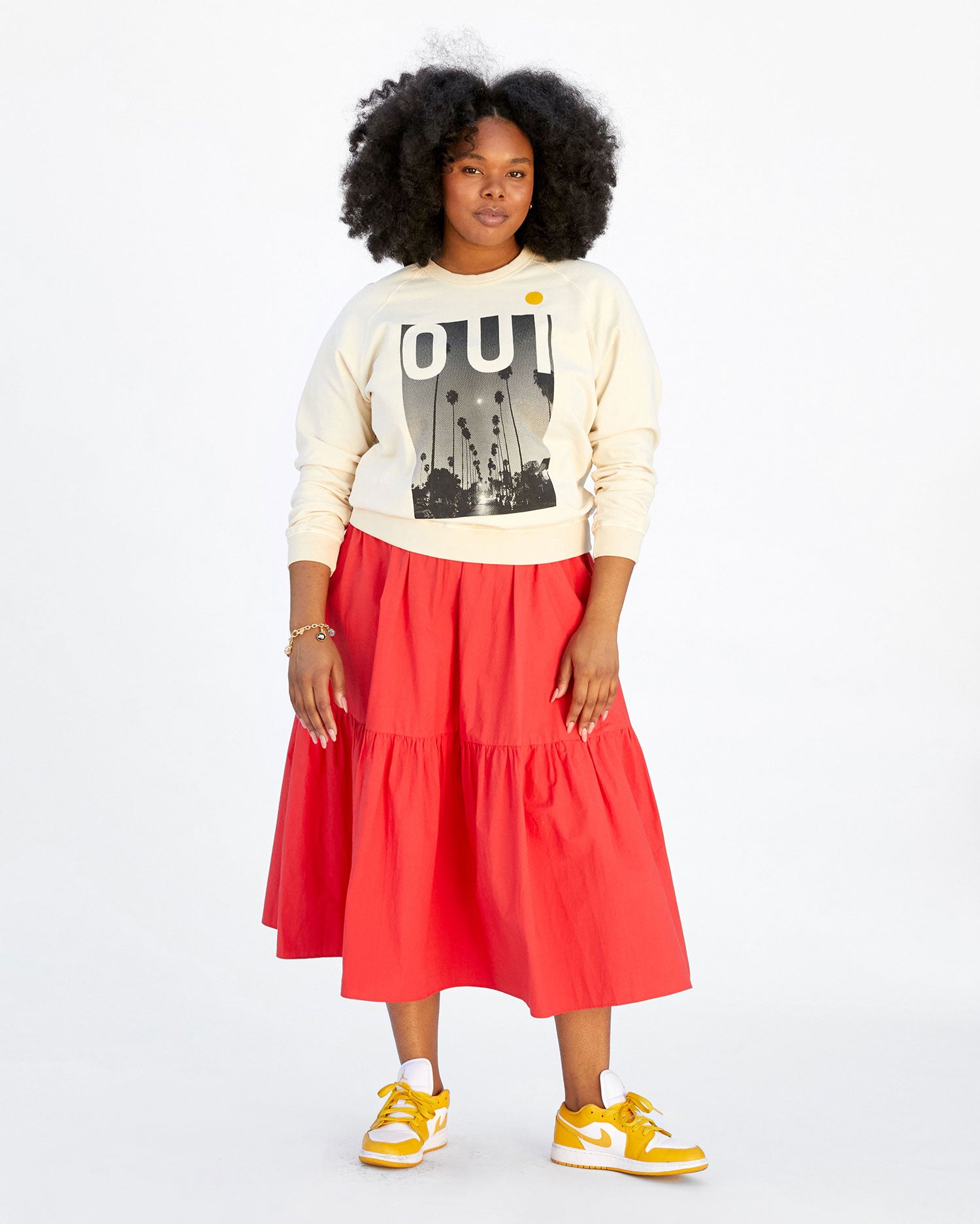 candice wearing the Cream Oui Sweatshirt with a midi length orange tiered skirt and yellow jordans