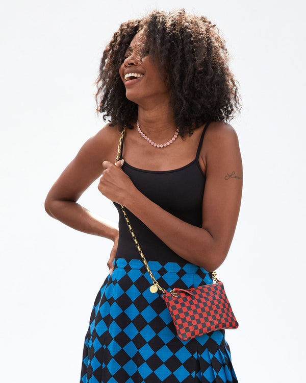 Mecca wearing the Red and Navy Checker Wallet Clutch w/ Tabs  crossbody with an added strap over her black tank top and black and blue diamond patterned skirt