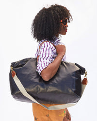 Mecca Carrying the Black Weekender  by it's Shoulder Strap