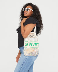 Candice carrying the Natural with Bon Vivant Woven Netty on her shoulder. she's wearing jeans and the black rattan maxine blouse