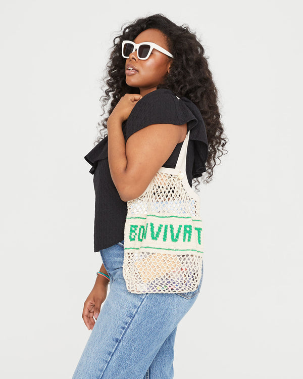 Candice carrying the Natural with Bon Vivant Woven Netty on her shoulder. she's wearing jeans and the black rattan maxine blouse
